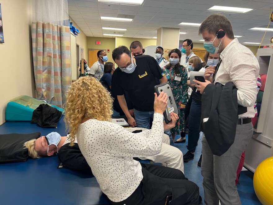 Physical therapist Serhii Khuda, right, and his colleagues tested out devices in the Tampa VA's spinal cord injury unit with help from a staff member.