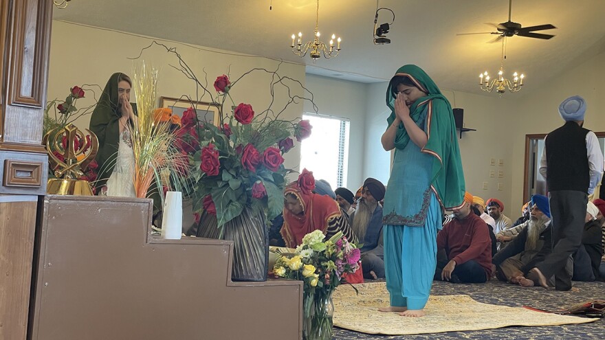 As people filed into the room, it’s tradition to bow towards the holy book, which is placed on an elevated surface and covered by a canopy. People also place money or other gifts at the front of the takhat. (Carter Barrett/WFYI)