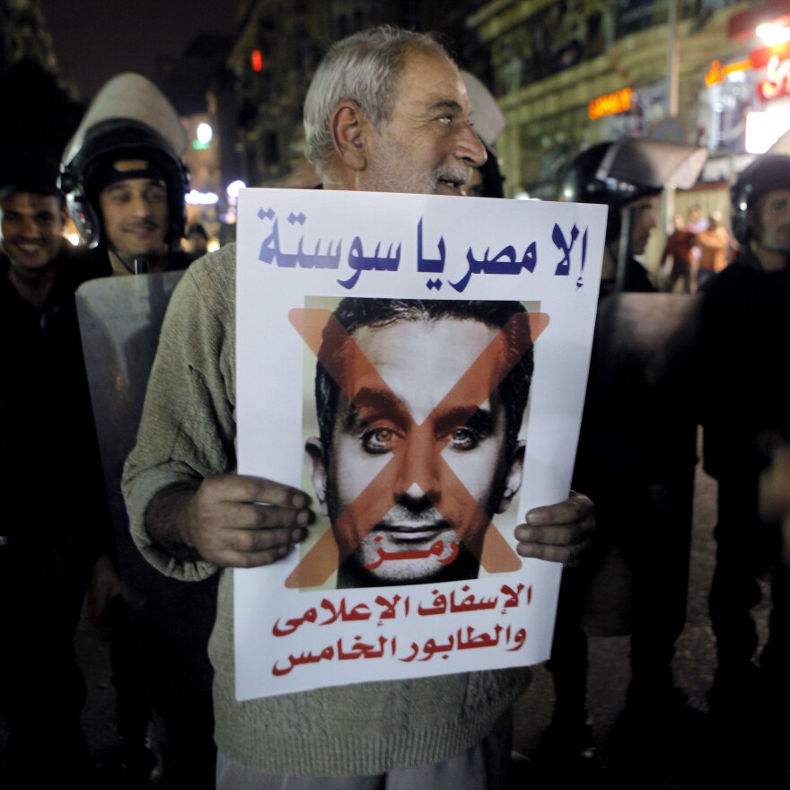 A supporter of Sissi holds a poster with a photo of Bassem Youssef, the man known as "Egypt's Jon Stewart," during a protest in Cairo. The sign reads, "not Egypt, you are degrading to the media, fifth column."