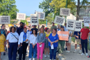 Supporters hold signs at a press conference and rally on UMKC's campus calling for higher wages for university workers.
