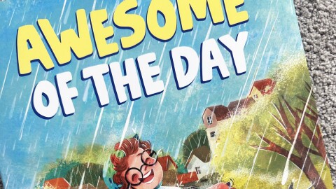A book titled Awesome of the Day has an illustration of two children riding bikes through a puddle.