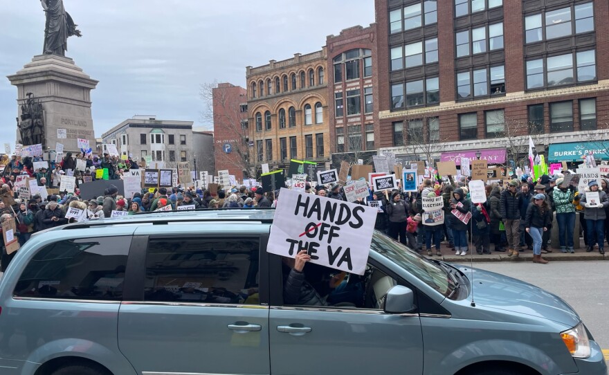 A car drives by on Congress Street holding a sign at the Hands Off protest in Portland, Maine on April 5, 2025.