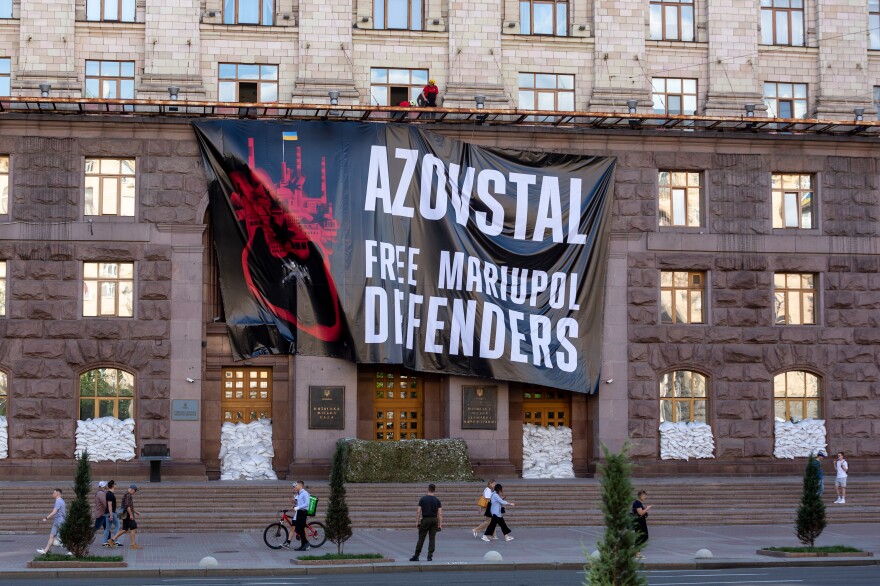 A large billboard with a sign saying "Azovstal. Free Mariupol Defenders" is being hanged on a Kyiv city building, on June 8.