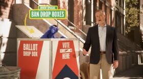 a man stands next to a box that has a puppet peeping out of it