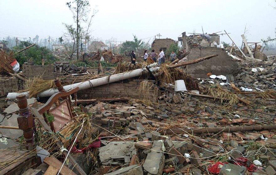 Residents walk in the rubble of destroyed houses after Thursday's tornado.