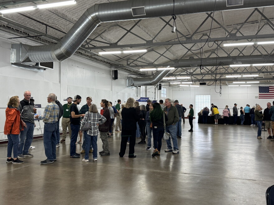 A crowd of people inside a large building. People are looking at signs and talking in groups. 