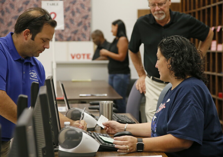 Summerlinn Muhammad, right, elections assistant, checks in Jason Soper, right, for early voting in Oklahoma City, Thursday, Aug. 18, 2016. 