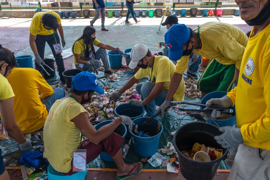 Volunteers sort trash items in a brand audit of plastic waste in Navotas, Manila. They keep track of the brands they find and publish results on the Web. Their goal is to pressure companies to change their plastic packaging.