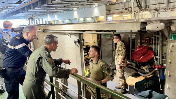 French Commander Jocelyn Delrieu, captain of the LDH Dixmude, and Navy Adm. Doug Perry talk to the crew of a French landing craft in the well deck of the French ship.