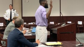 man at courtroom podium takes oath 