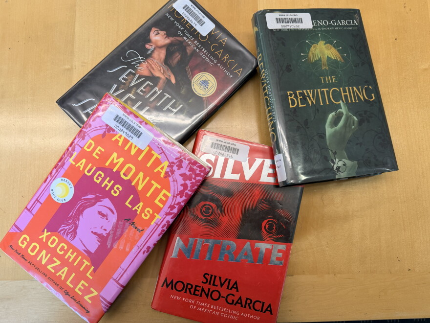 Four library books arranged on a wooden table: Anita de Monte Laughs Last, The Seventh Veil of Salome, Silver Nitrate and The Bewitching.