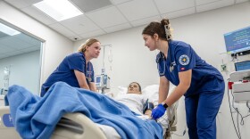 Marquette University nursing students practicing in a clinical setting using a mannequin. Nursing students are at risk of being able to take out less in student loans if Congress no longer designates graduate programs as "professional" programs.