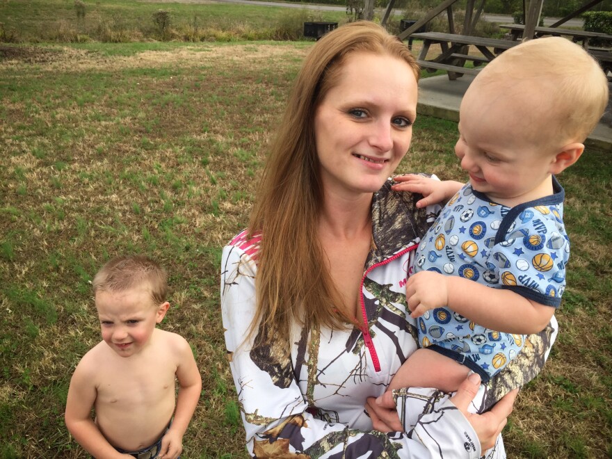 Brittany Crowe just completed an addiction treatment program that helped her regain custody of her children. Here she holds Allan, who was born with neonatal abstinence syndrome, as her son James stands behind them.