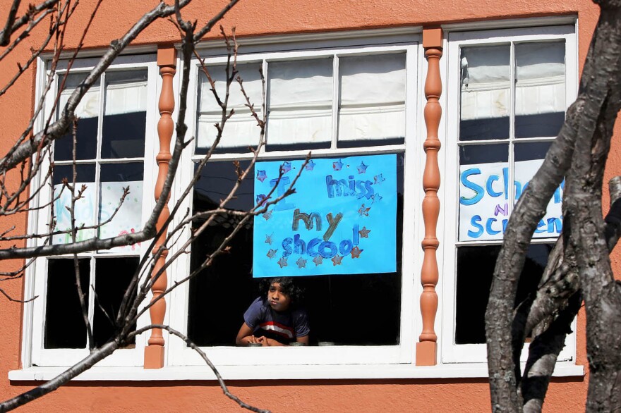 Jeevan Guha, 6, poses for a portrait near his homemade sign in San Francisco. The sign reads, "I miss my school."