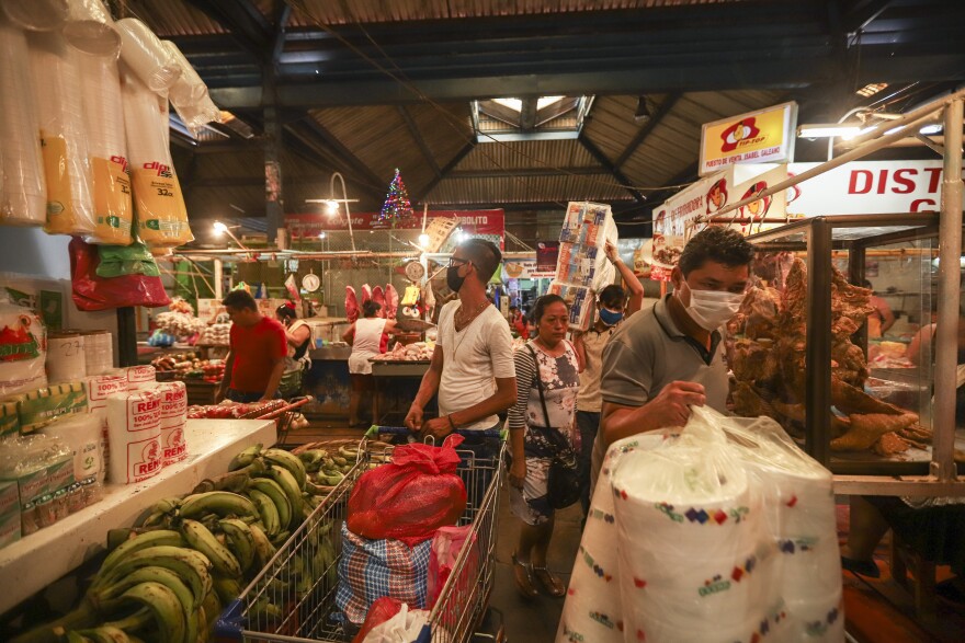 Customers, some wearing protective face masks, shop at a popular market in Managua, Nicaragua, Tuesday, April 7, 2020. Restaurants are empty, there's little traffic in the streets and beach tourists are sparse headed into Holy Week despite the government's encouragement for Nicaraguans to go about their normal lives. (AP Photo/Alfredo Zuniga)