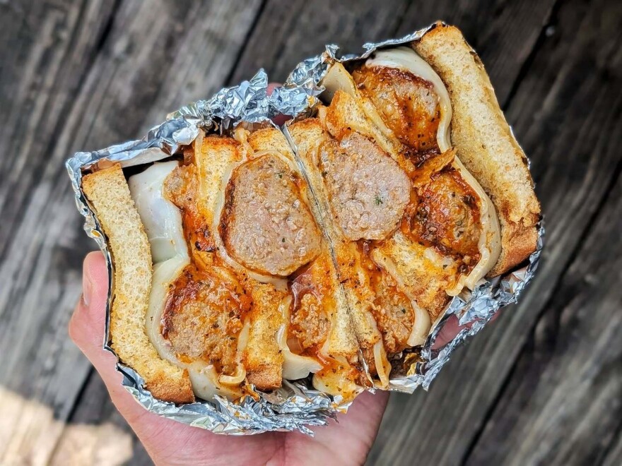 A hand holds a sandwich cut in half so the inside is visible.