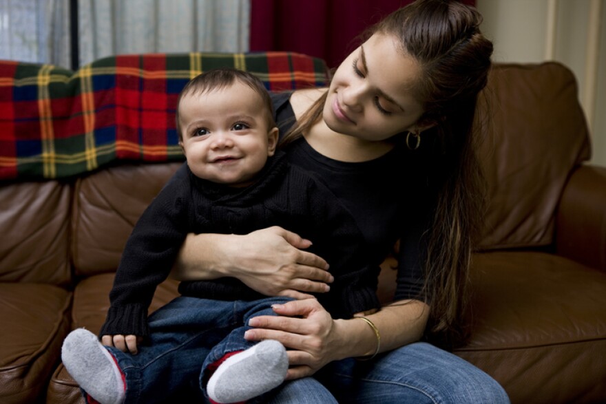 Little Hispanic baby boy sitting on a young mother's lap at home. Copy space. CLICK FOR SIMILAR IMAGES AND LIGHTBOX WITH MORE CHILDREN. http://www.quavondo.com/thumbs/IStockLightboxKids.jpg