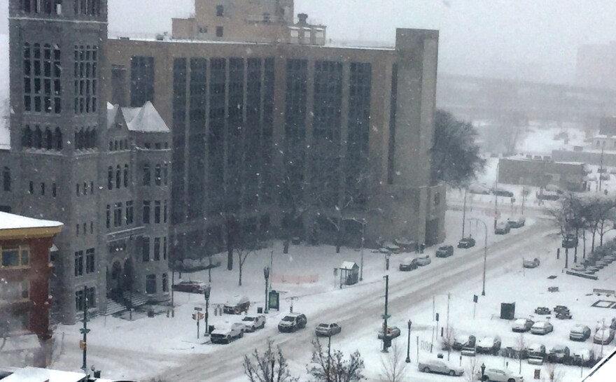 Cars covered in snow line the outside of a building.