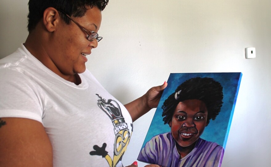 Kenrich Henderson gazes at a portrait of her daughter Jamyla Bolden. The painting is a gift from St. Louis artist Jane Martin and an organization called Faces Not Forgotten that produces portraits of children killed by gun violence. 