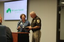 A police officer and a lady stand at a podium. 