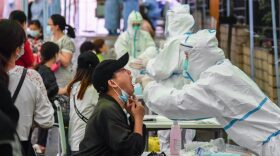 A medical worker takes a swab sample from a resident to be tested for the COVID-19 coronavirus in Wuhan in China's central Hubei province on May 14, 2020. - Nervous residents of China's pandemic epicentre of Wuhan queued up across the city to be tested for the coronavirus on May 14 after a new cluster of cases sparked a mass screening campaign. 