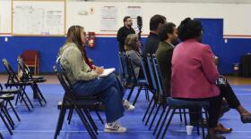 People sit in plastic chairs