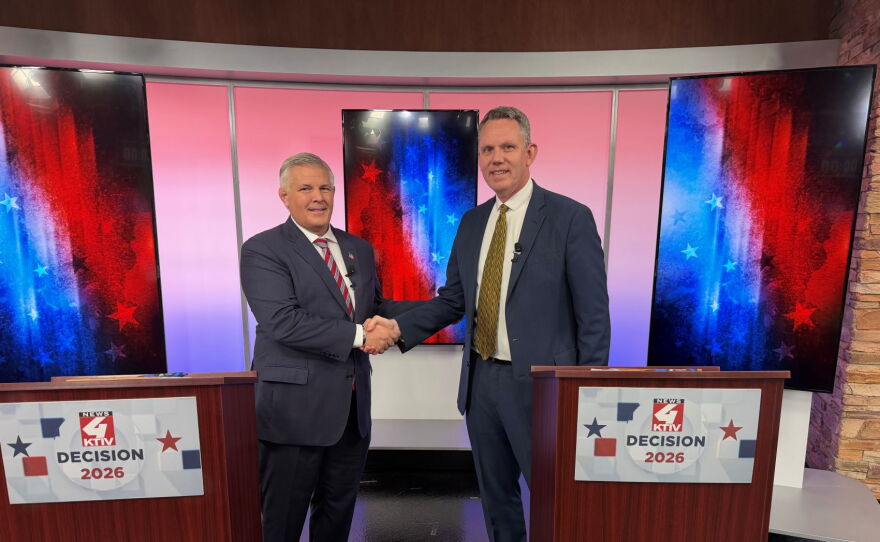 Two political candidates shake hands before a political debate. One on the left is shorter than the man on the right.