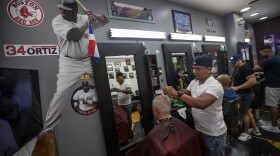 With the walls adorned with images of Big Papi, Gino Almonte gives a haircut to a patron at MLB Barbers on Tremont Street, where David Ortiz gets his hair cut regularly. (Jesse Costa/WBUR)