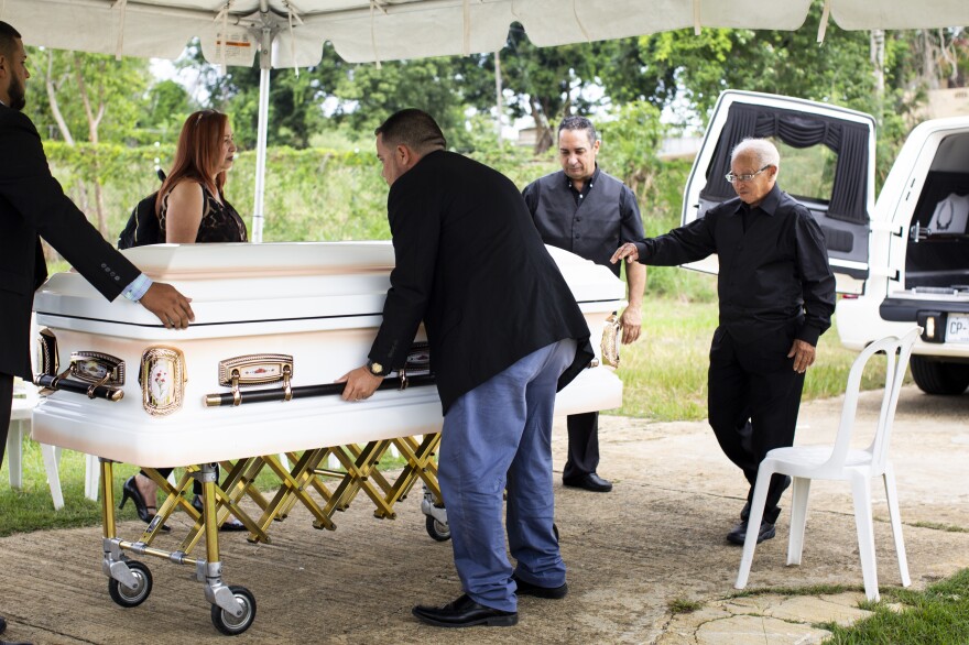 Armando Colón (second from right) helps lift his mother's casket out of the hearse at a cemetery 40 minutes away from Lares.