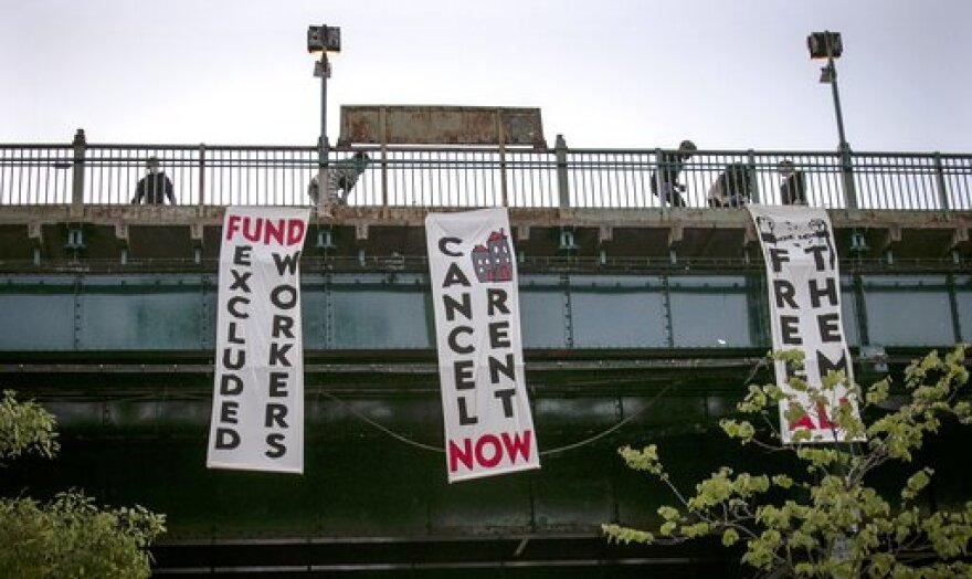 FILE - In this May 21, 2020, file photo, people from a support organization for immigrant and working class communities unfold banners, including one advocating rent cancelation, on a subway platform in the Queens borough of New York during a vigil memorializing people who died from coronavirus. The pandemic has shut housing courts and prompted authorities around the U.S. to initiate policies protecting renters from eviction. But not everyone is covered, and some landlords are turning to threats and harassment to force tenants out. (AP Photo/Bebeto Matthews, File)