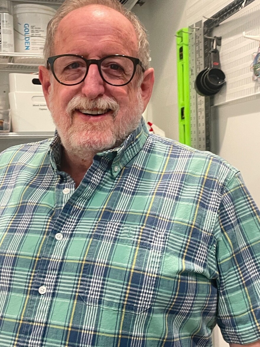 artist Tim McKay wears a green plaid button-down shirt and glasses as he smiles for the photo.