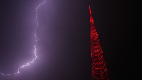 Lightning lights up the sky behind a television tower as a thunderstorm moves through the area Thursday, April 23, 2026, in Kansas City, Missouri.