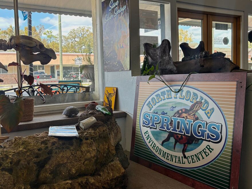 A sign for the North Florida Springs Environmental Center is displayed inside the Florida Springs Institute welcome center. Part of a manatee skeleton exhibit can also be seen in the space. (Ornella Moreno/WUFT News)