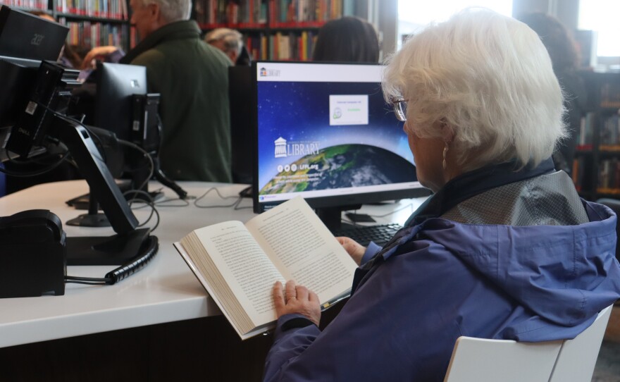 A older women sitting in at a table reading a book at the Portland Library