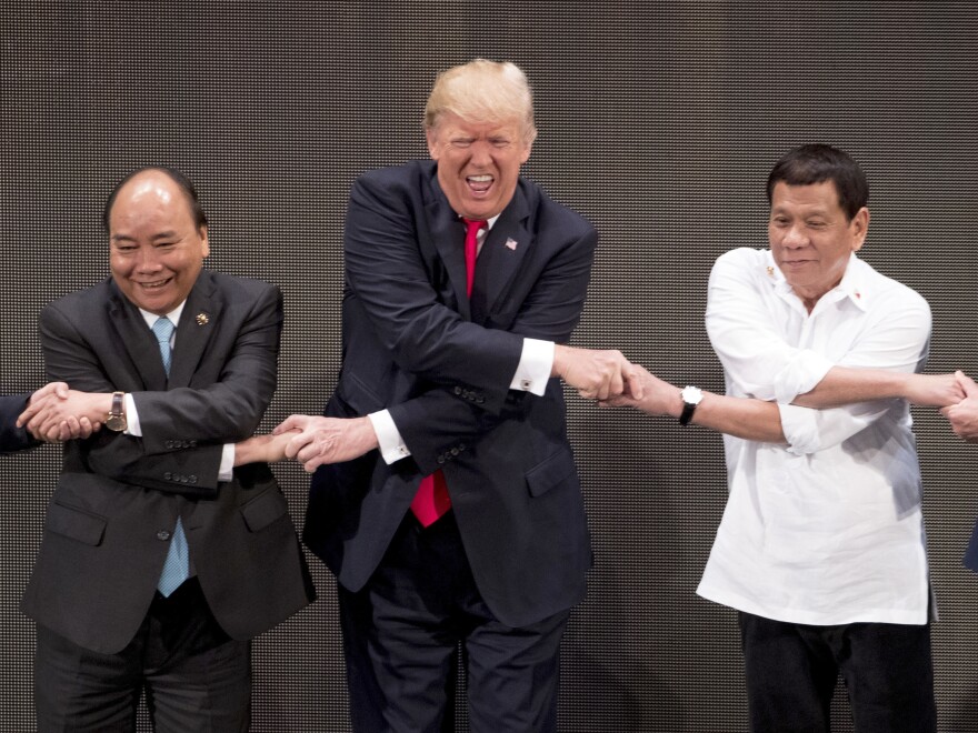 President Trump reacts as he does the "ASEAN-way handshake" with Vietnamese Prime Minister Nguyen Xuan Phuc (left) and Philippine President Rodrigo Duterte on stage during the opening ceremony at the ASEAN Summit at the Cultural Center of the Philippines on Monday.