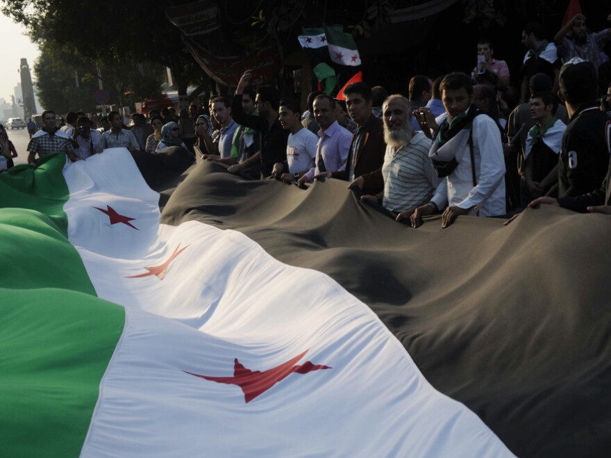 Pro-democracy protesters, holding a huge pre-Baath era Syrian flag outside the Arab league headquarters in Cairo on November 2, 2011.