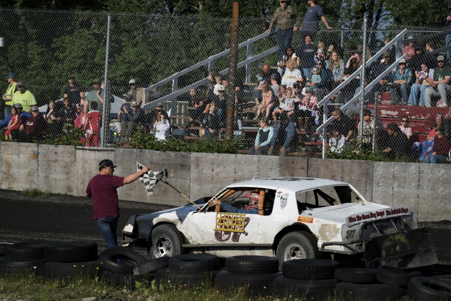 Craig Dehart hands the checkered flag to Jascha Zbitnoff for winning the second heat of a race on July 11, 2026.