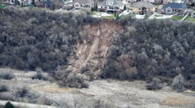  A row of homes in Layton sit atop a bluff, while a section of dirt is exposed below due to a landslide.
