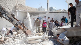 Syrians search for survivors under the rubble of a destroyed house after a barrel bomb was dropped from an air force helicopter in Saraqeb on July 20.