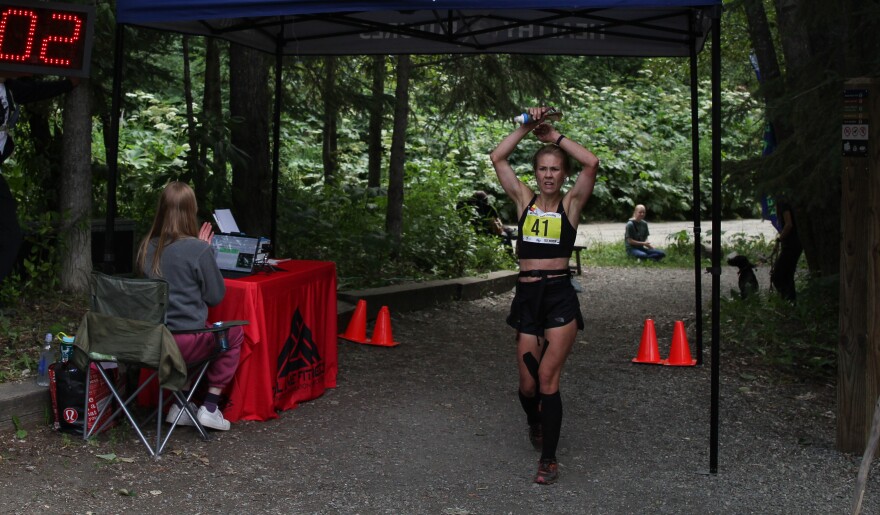 Shauna Severson crosses the finish line, arms raised above her head.