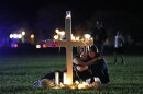 Two people comfort each other as they sit and mourn at one of seventeen crosses, after a candlelight vigil for the victims of the Wednesday shooting at Marjory Stoneman Douglas High School, in Parkland, Fla., Thursday, Feb. 15, 2018. Nikolas Cruz, a former student, was charged with 17 counts of premeditated murder on Thursday. (AP Photo/Gerald Herbert)