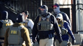 Law officials spread out through an apartment complex during a raid Wednesday, Feb. 5, 2025, in east Denver.