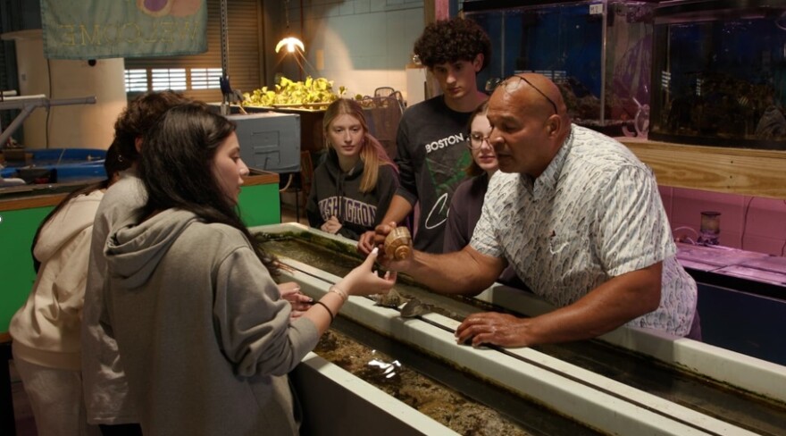 Teacher Leonard Baker, right, examines a crustacean while teaching aquaculture, the science of plants and animals in water, at Cranston High School West.