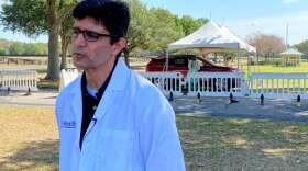 Dr. Michael Lauzardo, an expert on infectious disease and global medicine, speaks to the media as drive-thru testing takes place behind him in The Villages. Photo: Joe Byrnes