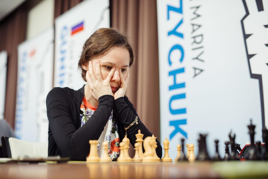 Woman focusing on a chess game.