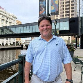 Retired Nicolet High School social studies teacher Mark Schill in front of the Milwaukee River in downtown Milwaukee, Wisconsin. 
