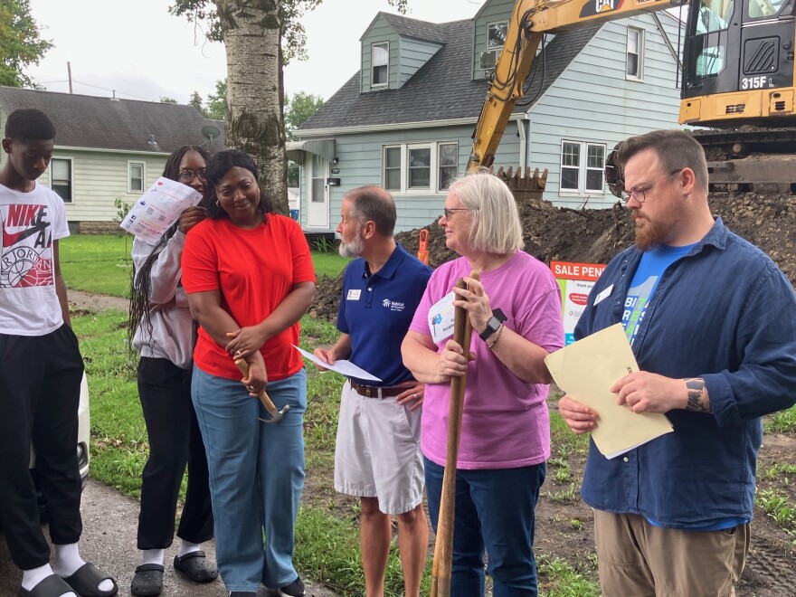 Tom Fisher-King (center), CEO of Habitat for Humanity Quad Cities, looks to new homeowner Hugette during a ceremonial groundbreaking in East Moline, Aug. 15, 2026. Looking on are Zach Currier, Habitat family services coordinator, and Hugette's voilunteer mentor, Belinda Holbrook.