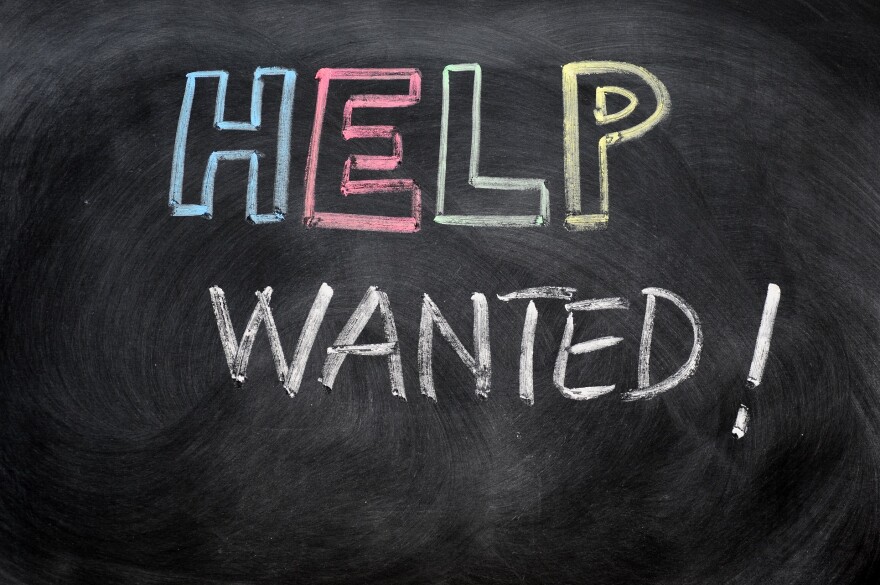 Help wanted message written in chalk on a blackboard