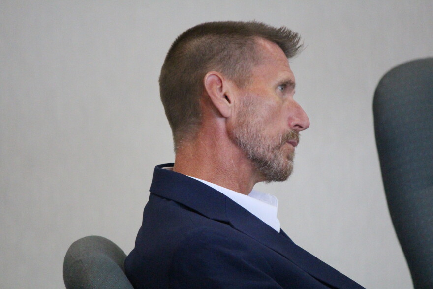 A man in a blue suit jacket and white shirt.