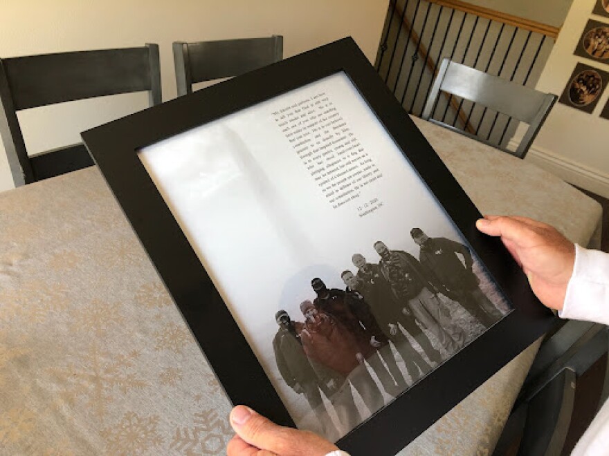 Casey Roberts holds a framed photo of a trip that some members of United Citizens' Alarm took to Washington, D.C. last year.